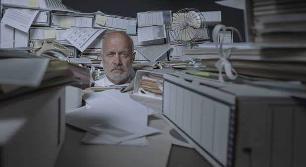 Mann im Office mit Aktenstapeln